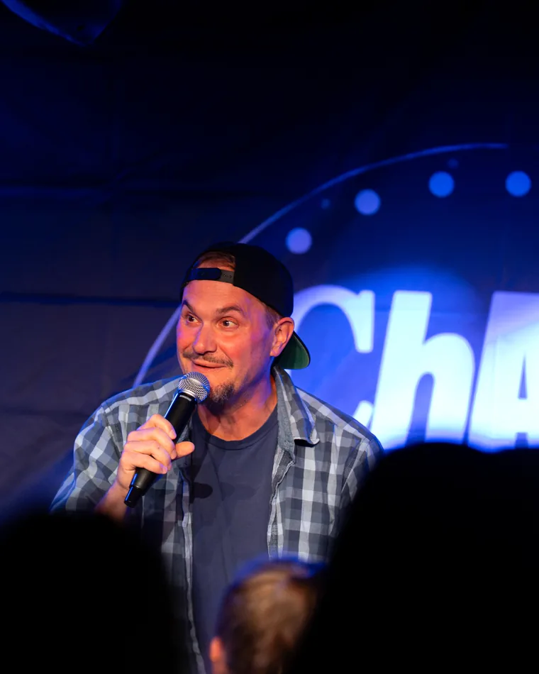 Der Host am Mikrofon vor dem Leuchtschild
