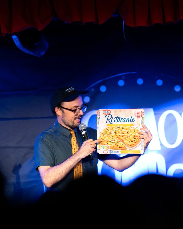 Comedian mit einem Pizzakarton auf der Bühne