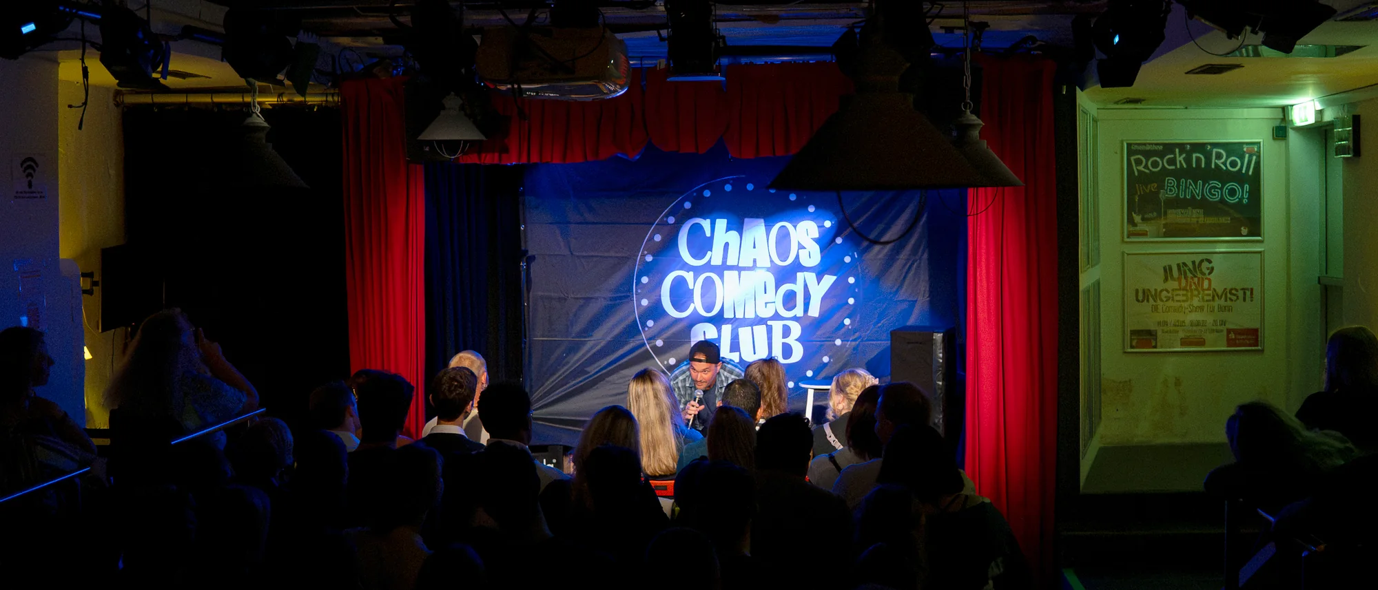 Voller Saal beim Chaos Comedy Club, Blick von hinten über das Publikum auf die beleuchtete Bühne